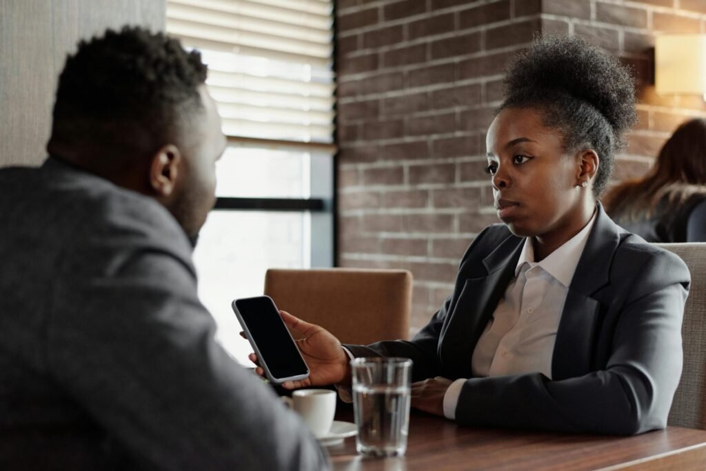 Two business professionals engage in a serious conversation while seated in a modern café.